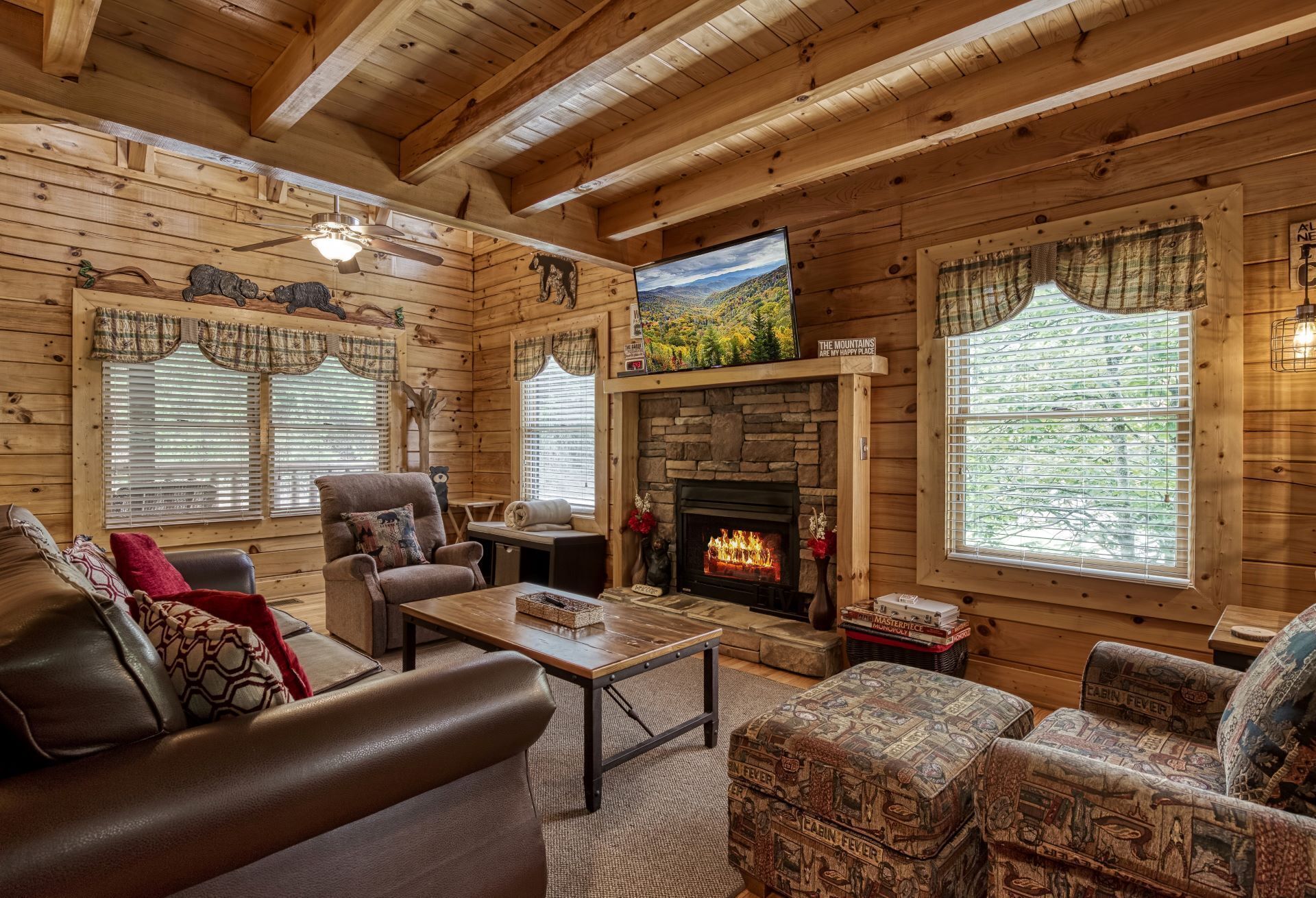 Un intérieur de chalet chaleureux avec des murs en bois, une cheminée en pierre, un téléviseur et des sièges confortables.