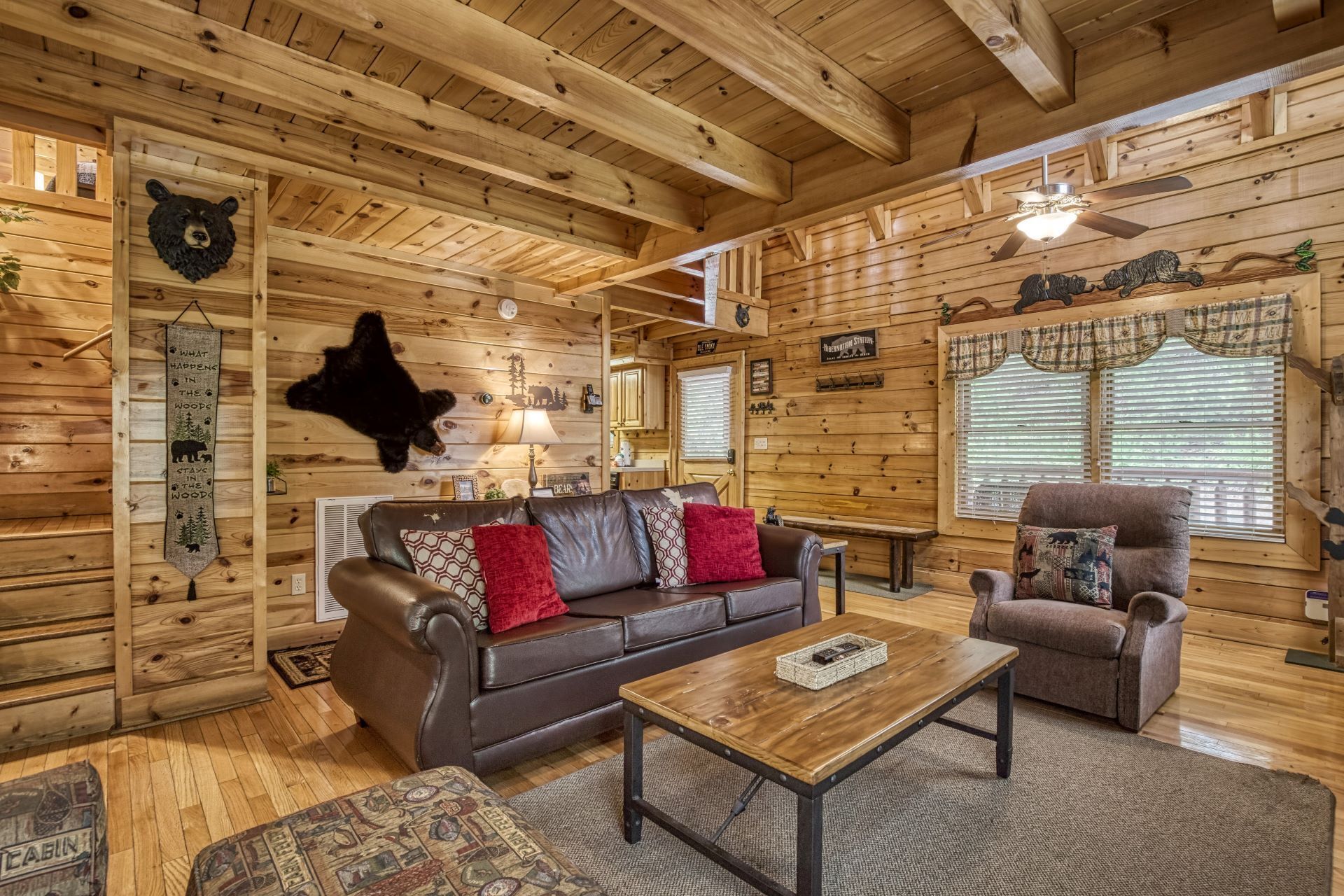 L’intérieur chaleureux d’un chalet avec un plafond en bois, un canapé en cuir, une table basse et un fauteuil.