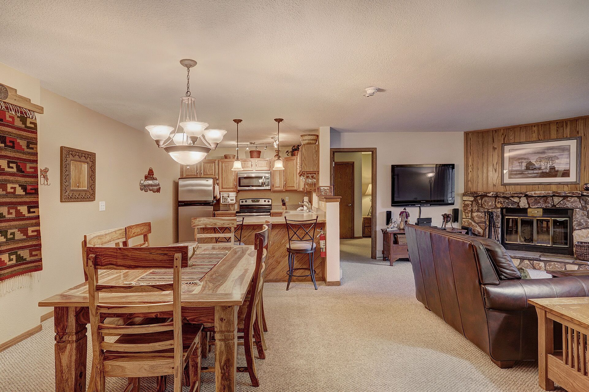 A spacious living room with a fireplace, a dining area with wooden furniture, and a kitchen with modern appliances.