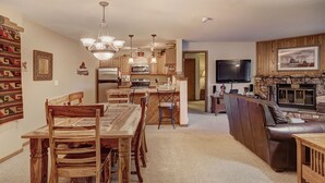 A spacious living room with a fireplace, a dining area with wooden furniture, and a kitchen with modern appliances. - Centrally Located/Walk to Lifts/Pool and Hot Tub Access/Private Patio (Keystone)
