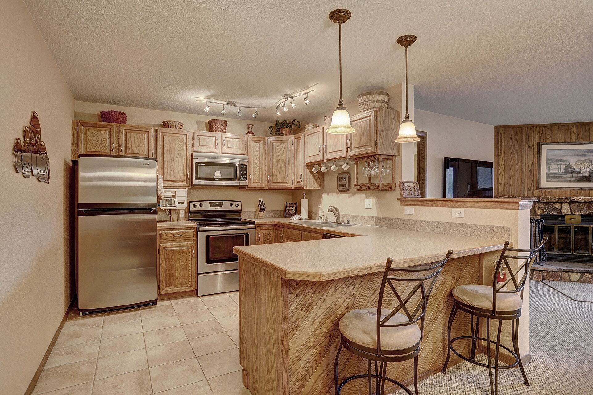 A kitchen with wooden cabinets, stainless steel appliances, a central island with bar stools, and pendant lighting.