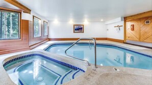 An indoor swimming pool with a wooden deck, a small hot tub, and a wooden wall with a framed picture. - Centrally Located/Walk to Lifts/Pool and Hot Tub Access/Private Patio (Keystone)