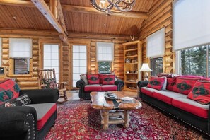 L’intérieur d’une cabane en rondins, avec un ensemble de canapés, une table basse et un tapis à motifs.