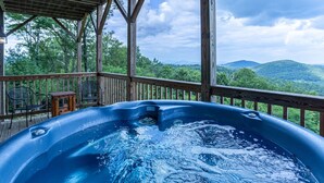 Ein Whirlpool auf einer Holzterrasse mit Blick auf Berge.