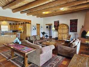 A rustic living room with wooden furniture, a fireplace, and a kitchen area with wooden cabinets.