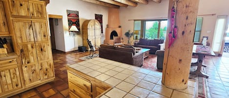 A spacious living room with a fireplace, wooden furniture, and a large window.