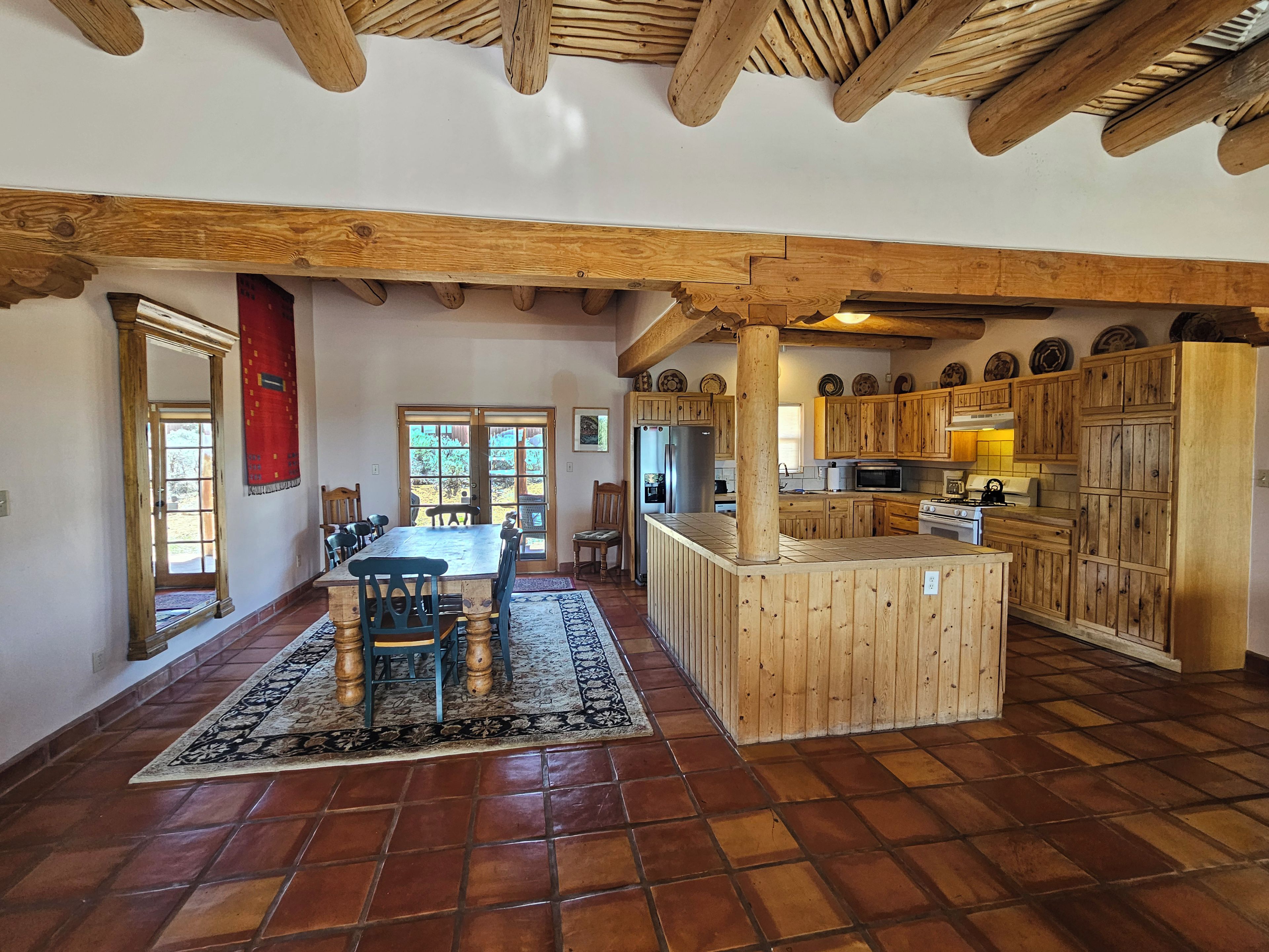 Une cuisine spacieuse dotée de meubles en bois, d’un îlot central et d’un coin repas avec une table et des chaises.