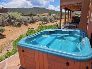 A hot tub in an outdoor setting with a view of a desert landscape and mountains in the background. - Heathers Hacienda 3 360 Views Hot Tub AC (Taos)
