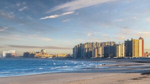 Un paysage urbain côtier avec de hauts immeubles, une plage et l’océan.