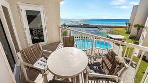 Ein Balkon mit Blick auf den Ozean, einem Pool und Sitzgelegenheiten im Freien.