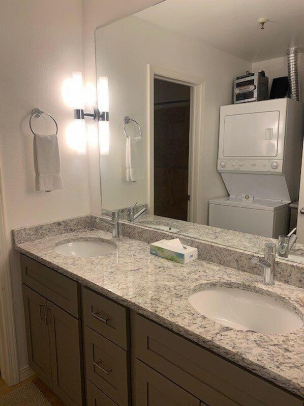 Un baño con dos lavamanos, un espejo y un perchero para toallas.
