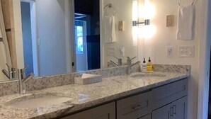 A bathroom with a large mirror, a sink, and a toilet. There are cabinets below the sink and a towel hanging on the wall. - JHRL - Balsam Lodge A8 - Great Location in the Aspens (Wilson)