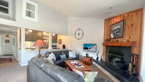 A modern living room with a grey leather sofa, a wooden coffee table, and a fireplace. - JHRL - Balsam Lodge A8 - Great Location in the Aspens (Wilson)