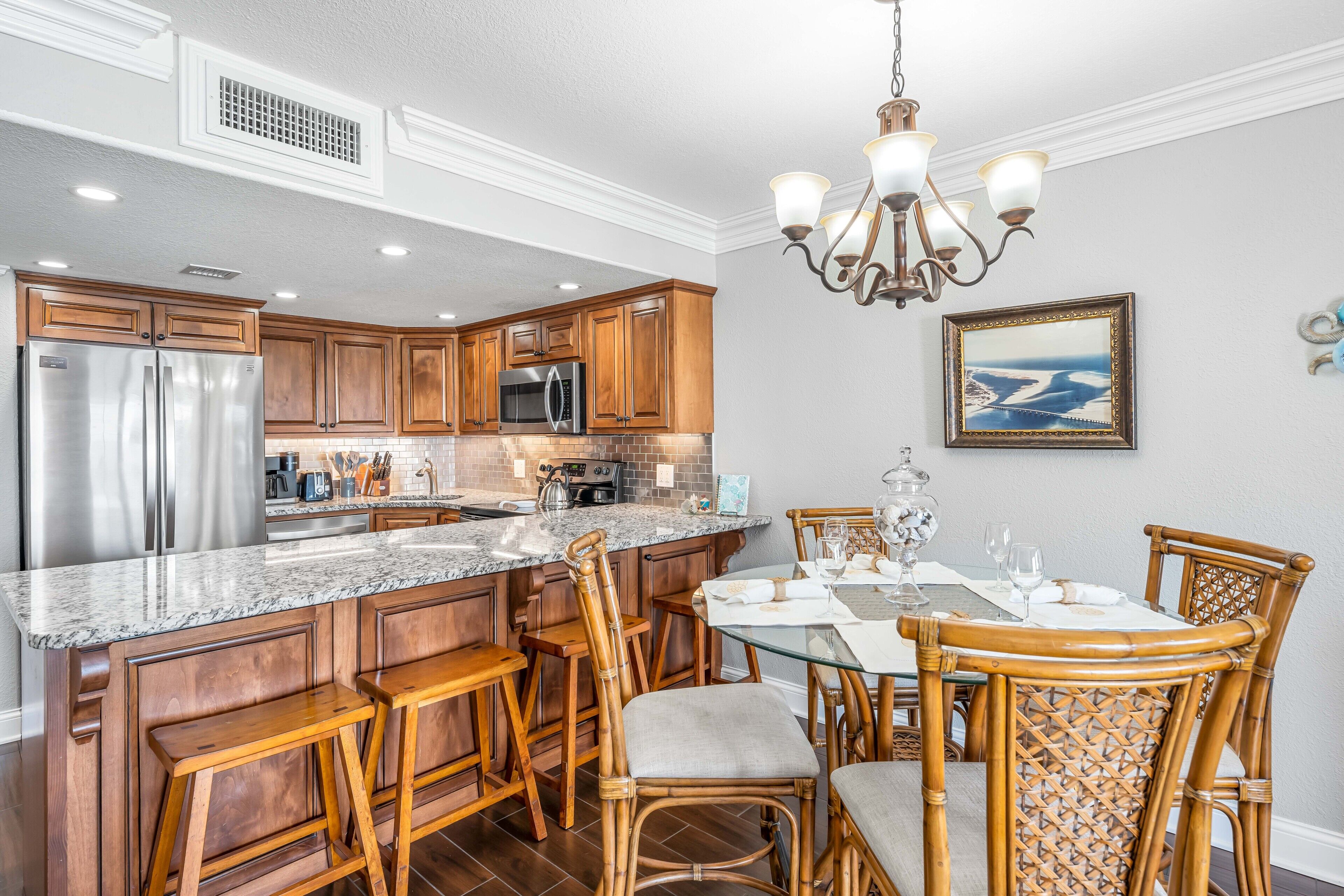 A kitchen with wooden cabinets, stainless steel appliances, and a dining area with wicker chairs and a glass table.