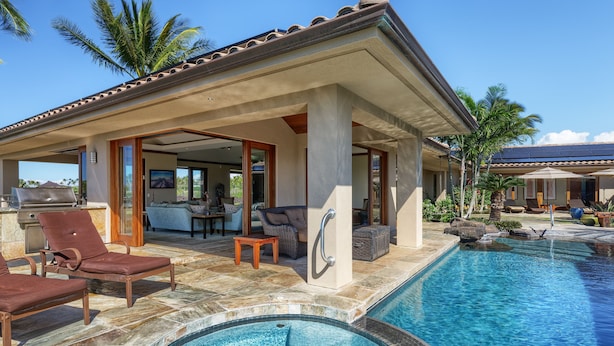 A poolside area with lounge chairs, a covered seating area, and a view of the pool.