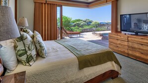 A bedroom with a large bed, a television, and a view of a pool and greenery.