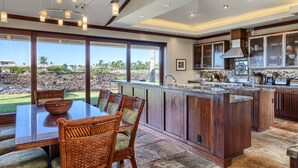 A spacious kitchen with a large island, dark wood cabinetry, and a view of the outdoors.