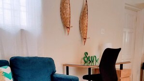 A living room with a blue sofa, a glass table with a white candle, and decorative items on the wall.
