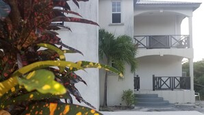 A building with a covered balcony and a staircase leading to an upper level.
