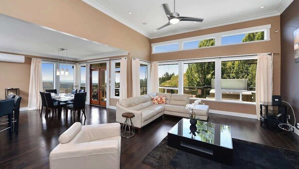 A spacious living area with a sectional sofa, a dining table, and a large window offering a view of the outdoors. - Nature's Gate Executive Estate (Victoria)