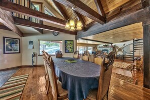 A dining area with a long table, chairs, and a chandelier.