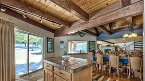 Una cocina amplia con armarios de madera, una isla grande y un comedor con sillas de madera y mantel azul.