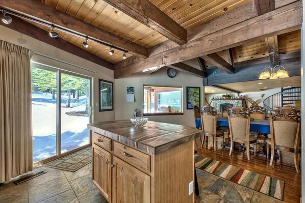 A spacious kitchen with wooden beams, a large island, and a dining area with chairs.
