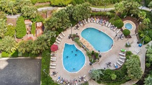 An aerial view of a resort with two swimming pools, surrounded by lounge areas and palm trees. - $150 activities - E-gift card when you book - Extra Deep Oceanfront Balcony | M1606 (Myrtle Beach)