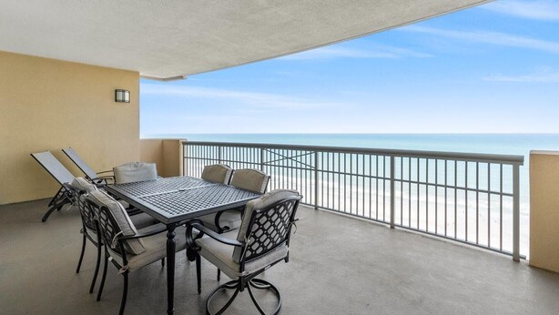 A balcony with a table and chairs, a view of the beach, and a railing. - $150 activities - E-gift card when you book - Extra Deep Oceanfront Balcony | M1606 (Myrtle Beach)