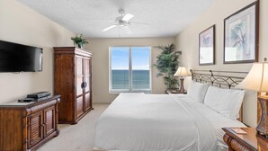A bedroom with a bed, a TV, a wardrobe, a ceiling fan, a window with blinds, and a plant. - $150 activities - E-gift card when you book - Extra Deep Oceanfront Balcony | M1606 (Myrtle Beach)