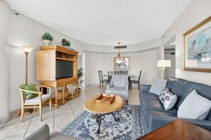 Ein Wohnzimmer mit Sofa, Couchtisch, TV-Stand und Essbereich.
