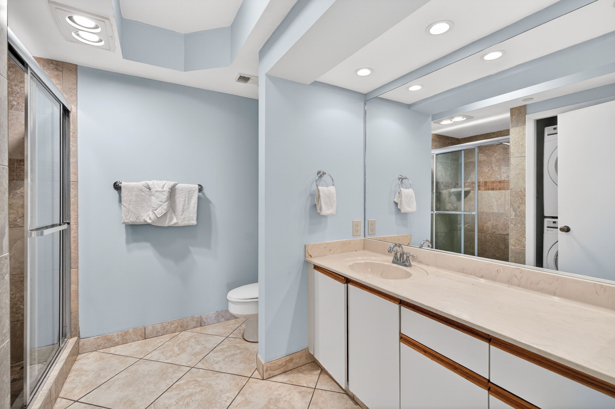 Une salle de bain moderne avec un grand miroir, un lavabo et des toilettes.