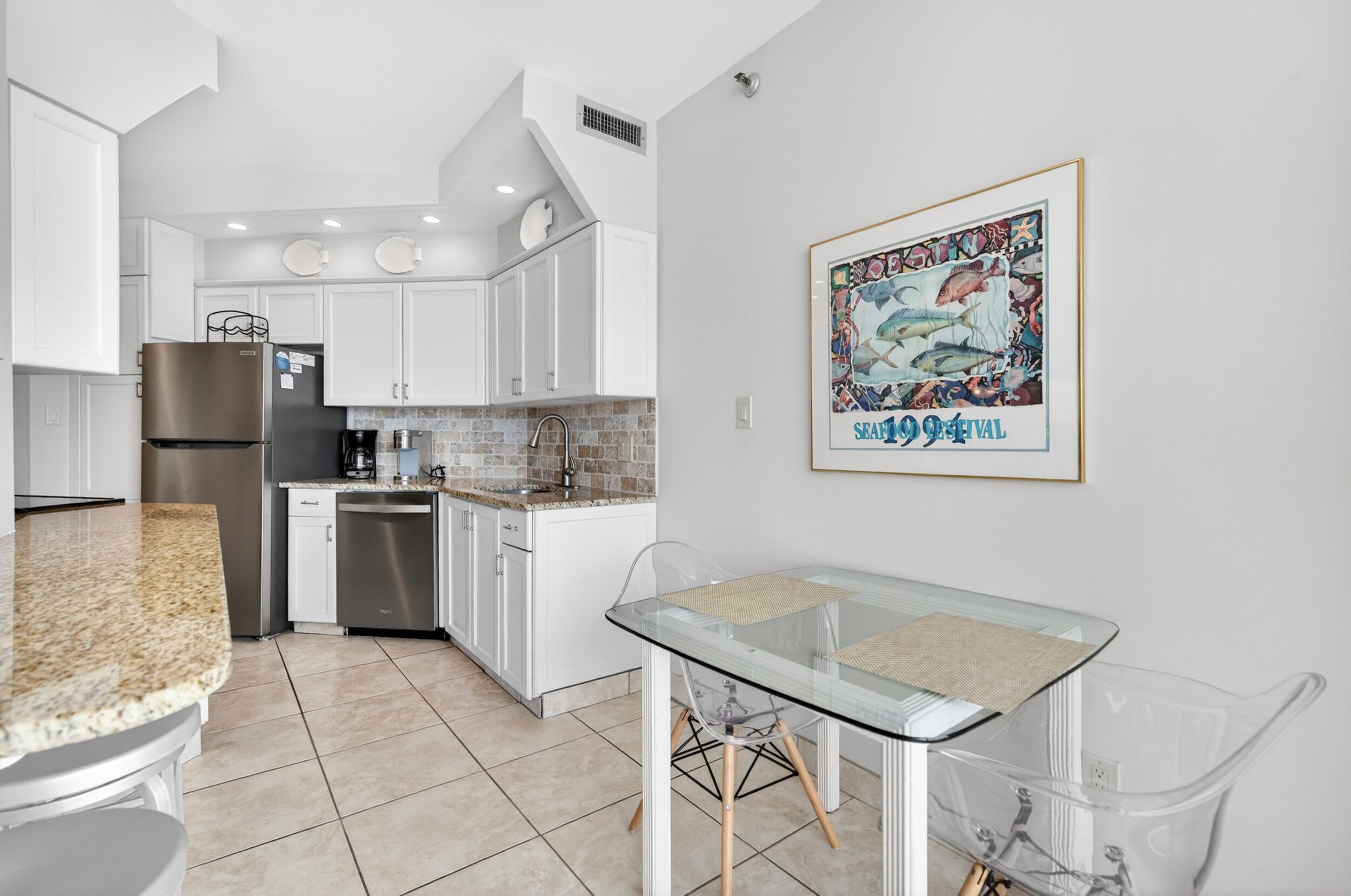 A modern kitchen with white cabinets, stainless steel appliances, and a glass dining table.