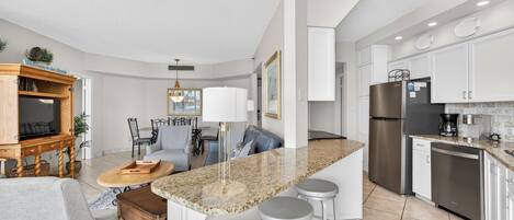 A modern kitchen with a granite countertop, stainless steel appliances, and a dining area with a table and chairs.