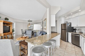 Una cocina moderna con encimera de granito, electrodomésticos de acero inoxidable y un comedor con mesa y sillas.