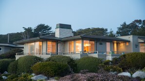 Una casa moderna con chimenea de piedra, ventanas amplias y un jardín cuidado.
