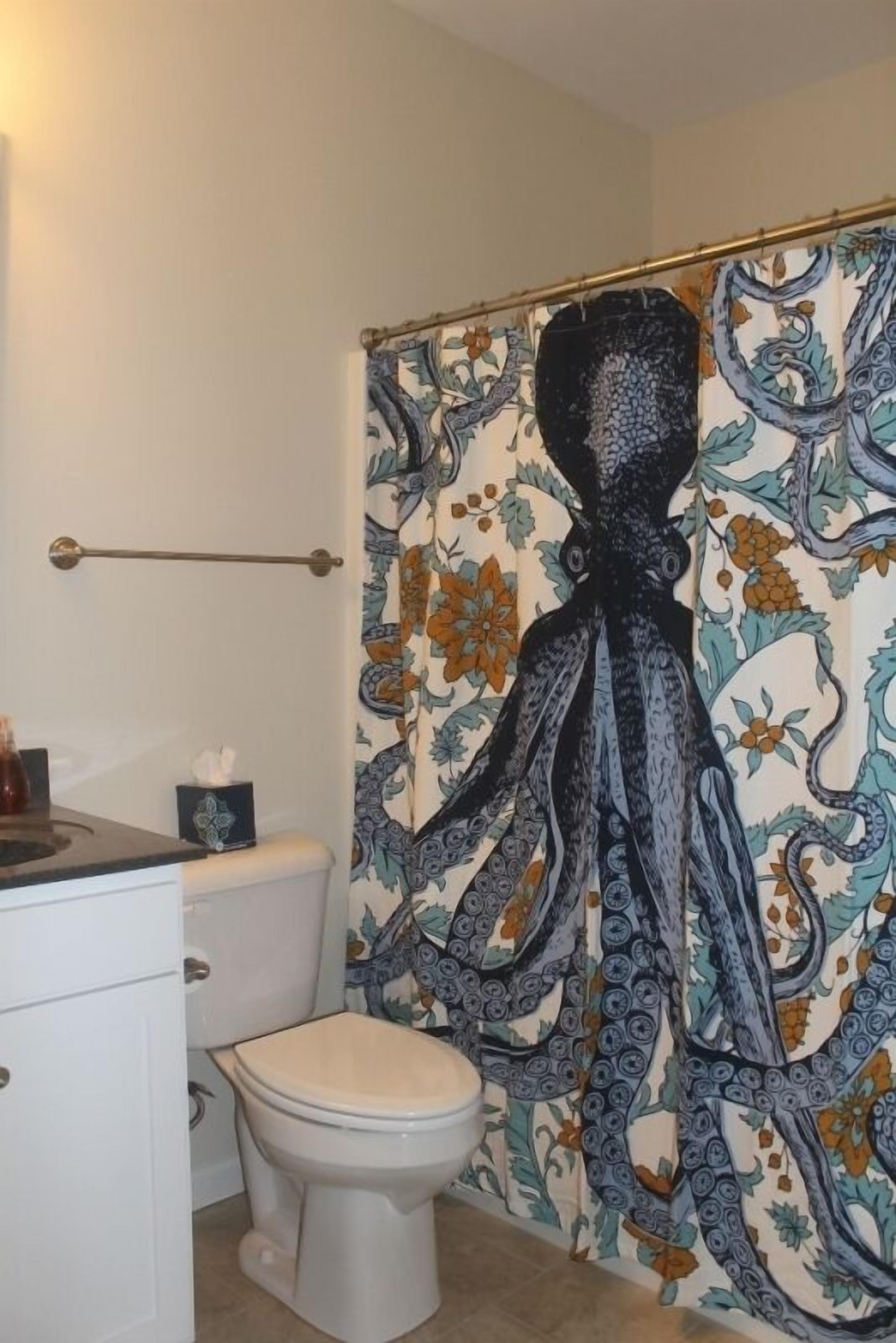 A bathroom with a toilet, a towel rack, and a shower curtain with a large octopus design.