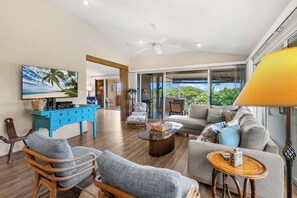 A spacious living room with a television, seating area, and a view of the outdoors.