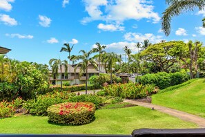 A resort with a well-maintained lawn, palm trees, and a building with a flat roof.