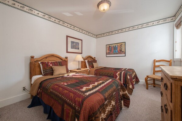A bedroom with two wooden beds, a nightstand, a dresser, and a chair.