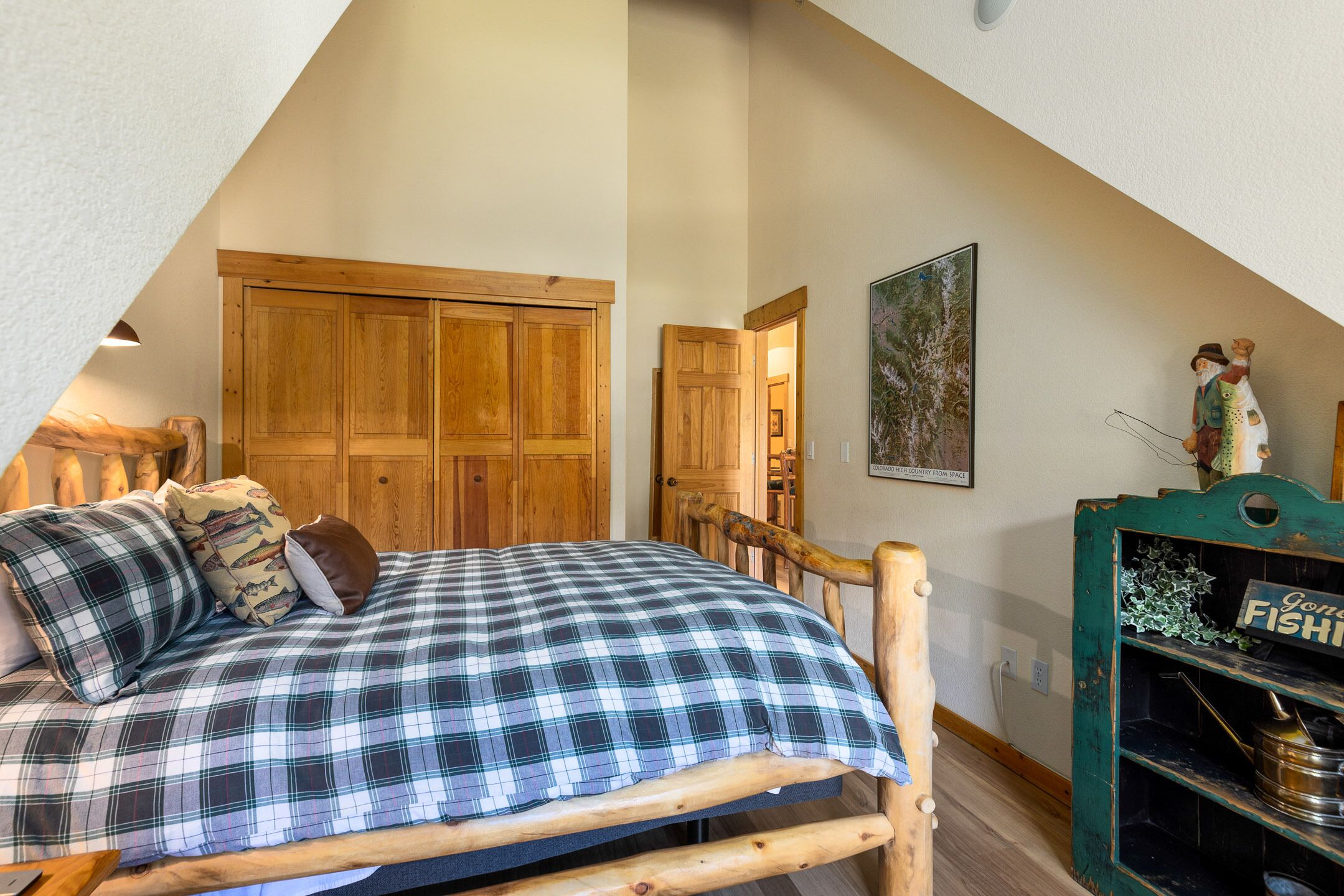 A loft bedroom with a wooden bed, a wooden wardrobe, and a green cabinet with a sign.