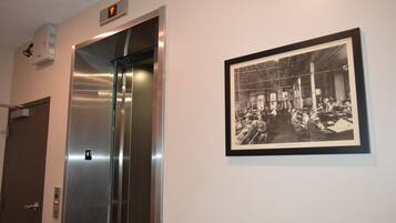 Un ascenseur doté d’un panneau de commande et d’une photographie historique encadrée accrochée au mur.