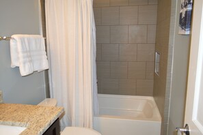 A bathroom with a shower, a bathtub, and a granite countertop. - 1890-1930 Historic Politics Themed condo, 2 blocks from French Quarter (New Orleans)