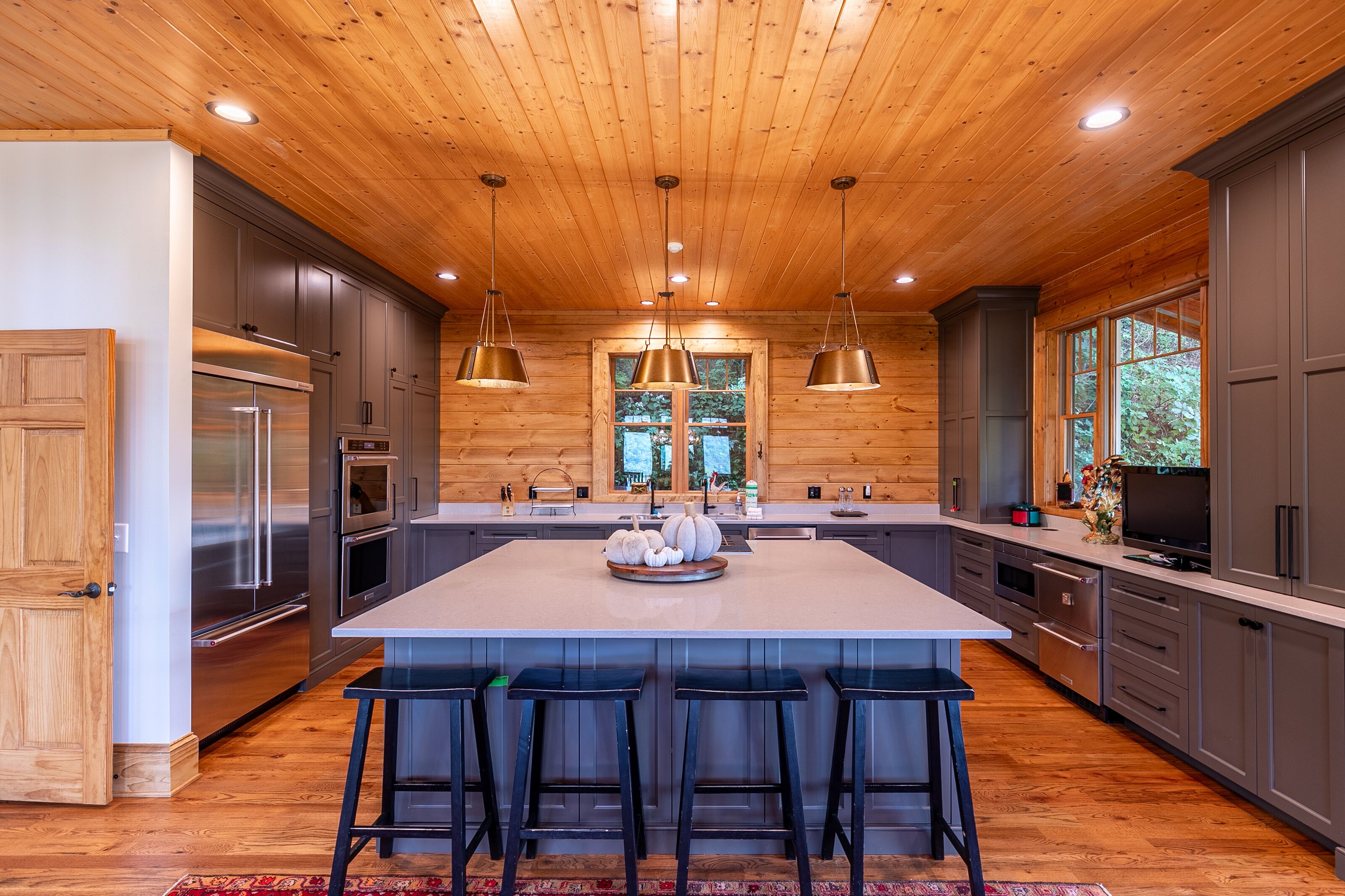 A chef-worthy kitchen built for a crowd, with a generous island, warm wood ceilings, and golden pendant glow.