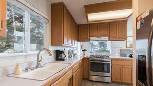 Une cuisine moderne avec des meubles en bois, une cuisinière en acier inoxydable et une grande fenêtre.