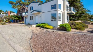 Une maison à deux étages, avec une façade blanche, un petit porche et un garage.