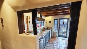 A kitchen with a tiled floor, wooden beams, and a window.