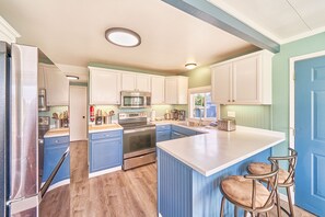 A kitchen with a central island, stainless steel appliances, and a blue and white color scheme.