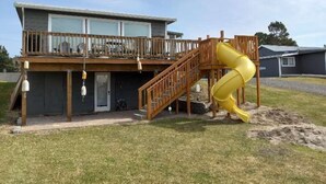 A two-story house with a wooden deck and a yellow slide. - PICKLEBALL, HOT TUB, Dogs Ok, Ocean View, Playset (SV1) (Long Beach)