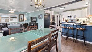 A modern kitchen with white cabinets, a glass dining table, and a bar area with stools. - PICKLEBALL, HOT TUB, Dogs Ok, Ocean View, Playset (SV1) (Long Beach)